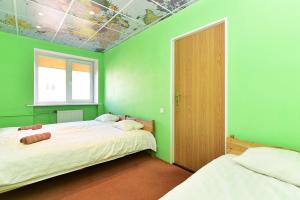 a green bedroom with two beds and a window at Travel Apartment in Ventspils