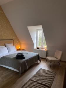 1 dormitorio con 1 cama, 1 silla y 1 ventana en Chambres d'hôtes du Bistrot des écuries en Cour-Maugis-sur-Huisne