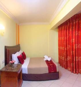 a bedroom with a bed and a desk and curtains at Sun Inns Hotel Batu Caves in Batu Caves