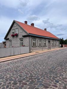 a building with a red roof on a cobblestone street at Apartamenti Kuldīgas Pilsdzirnavas in Kuldīga