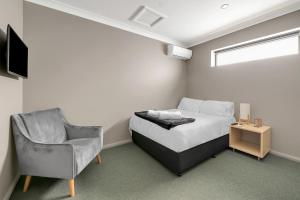 a bedroom with a bed and a chair and a television at Illinois Hotel in Sydney