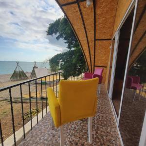 a yellow chair on a balcony with a view of the ocean at Дом с видом на море на Белом пляже in Novy Afon