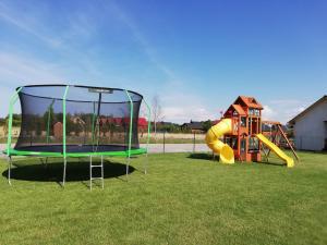 un parque infantil con cama elástica y tobogán en Domki Weekend, en Rusinowo