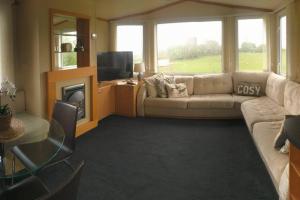 a living room with a couch and a tv at Plum Tree Lodge Set in 2 acres of Private Land in Coundon