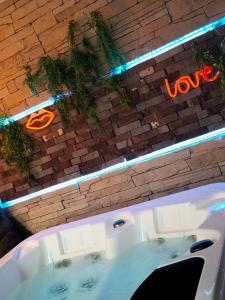 a white bath tub with a sign on a brick wall at Love room, L'idyle loft érotique détente in Callac +30 photos