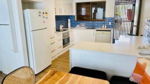 a kitchen with a white refrigerator and a table at #7 Highlander, Kings Beach - Beachfront Complex in Caloundra