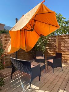an orange umbrella and chairs on a wooden deck at Chez Adri et Léa in Biguglia