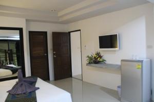 ein Wohnzimmer mit einem Kühlschrank und einem TV an der Wand in der Unterkunft The Seashore Kamala Service Apartment in Kamala Beach