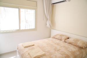 uma cama num quarto branco com uma janela em Dizengoff - Lovely family apartment 3 rooms. em Tel Aviv