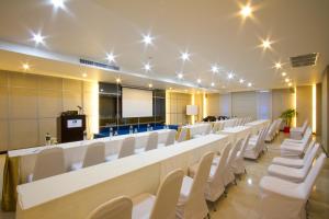 une salle de conférence avec une grande table et des chaises blanches dans l'établissement Andakira Hotel - SHA Extra Plus, à Patong Beach