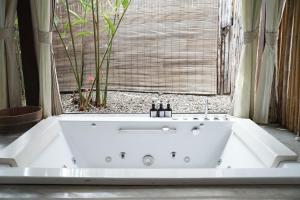 a white bath tub in a room with a window at Le Sen Boutique Hotel in Luang Prabang