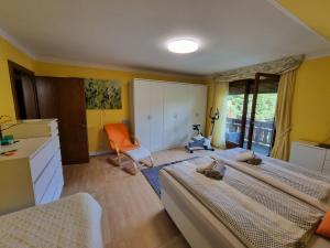 sypialnia z 2 łóżkami i pomarańczowym krzesłem w obiekcie Haus Flora - Ferienwohnung Bodensdorf w mieście Bodensdorf