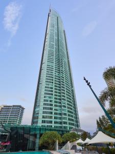 um arranha-céus alto e verde com palmeiras em frente em Serain Residences on 9 Hamilton Avenue em Gold Coast