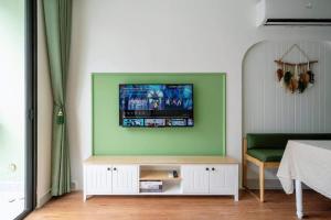 a living room with a tv on a green wall at Capsule Vinhomes Ocean Park in Hanoi