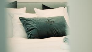 a black pillow on a bed with white pillows at B&B De Tiendeschuur in Evergem