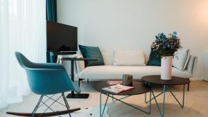 uma sala de estar com um sofá, uma cadeira e uma mesa em B&B De Tiendeschuur em Evergem