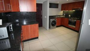 a kitchen with wooden cabinets and a washer and dryer at Accommodation Front - Immaculate 4 Sleeper with Ocean & Harbour Views in Durban