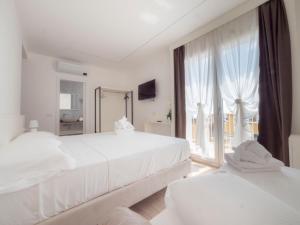 una camera bianca con due letti e una grande finestra di Hotel Continental a Pietra Ligure