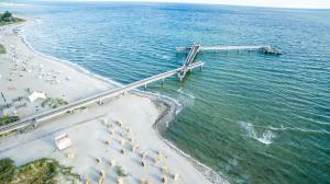 eine Luftansicht auf einen Strand mit Sonnenschirmen und einem Dock in der Unterkunft Ostseeferienparadies Heiligenhafen in Heiligenhafen