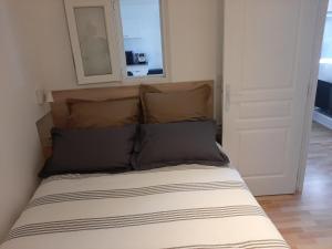 Una cama con dos almohadas y un espejo encima. en LOCATION APPART 45 M² - 2 CH AVEC JARDIN PRIVATIF en Gailhan