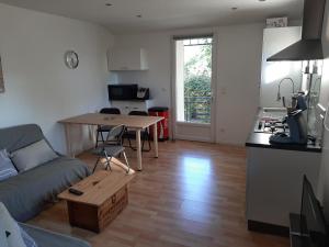 sala de estar con sofá, mesa y cocina en LOCATION APPART 45 M² - 2 CH AVEC JARDIN PRIVATIF en Gailhan