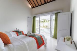 two beds in a white room with a window at Villa Shanti Bingin in Uluwatu