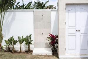 a white garage with a door and plants at Villa Shanti Bingin in Uluwatu