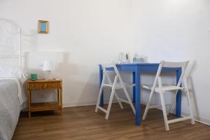 einen blauen Schreibtisch mit zwei weißen Stühlen neben einem Bett in der Unterkunft Terrasini 2000 Home Holidays in Terrasini