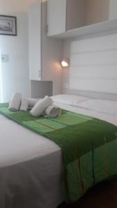 a large white bed with a green blanket on it at Hotel Imperiale in Cesenatico