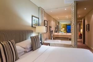 Royal Palm Hotel في ديربان: غرفة نوم بسرير وحمام مع حوض استحمام