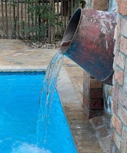 a water fountain pouring into a swimming pool at Kaoko Mopane Lodge & Campsite in Opuwo