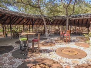 a patio with tables and chairs under a pavilion at Kaoko Mopane Lodge & Campsite in Opuwo