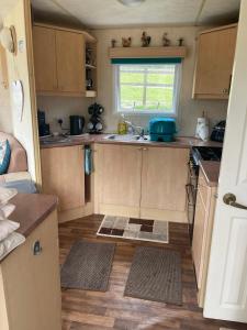 a small kitchen with wooden cabinets and a window at Pant yr onen holidays in Llandrindod Wells