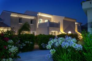 Il Borghetto Creative Resort في تروبيا: أمامه بيت أبيض كبير وبه زهور