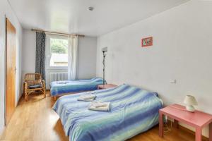 a bedroom with two beds and a table and a window at Le Lutin in Luchon