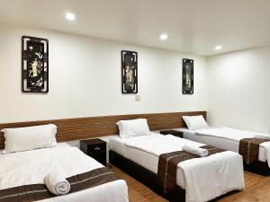 drie bedden in een kamer met witte muren bij Longzhu Guesthouse in Bangkok