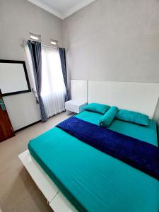 a bedroom with a bed with blue sheets and a window at Villa petit Tour in Batu