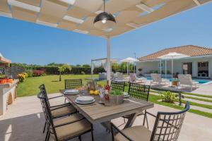 eine Terrasse mit einem Tisch mit Stühlen und einem Sonnenschirm in der Unterkunft Madini Luxury villa with private heated pool in Vanáton