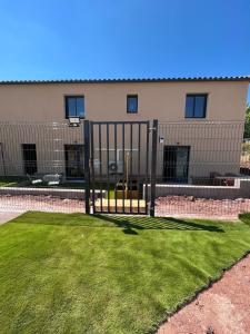 a fence with grass in front of a building at Désirée in Le Bosc