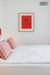 a white bed with two pillows and a picture on the wall at Villa Rossella in Locarno