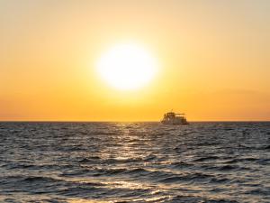 a boat in the ocean at sunset at Golden Star City Resort in Perea