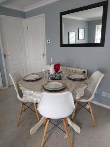 a dining room table with white chairs and a mirror at 238 Norton Park, Dartmouth 2 bed holiday home with free parking in Dartmouth