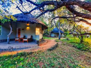 una pequeña casa con techo de paja y porche en Sefapane Lodge and Safaris, en Phalaborwa