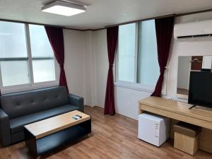 uma sala de estar com um sofá e uma televisão em Bricks Stay Jeju City & Aiport em Jeju