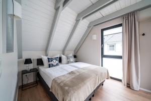 a bedroom with a bed and a large window at Haus Schlehe -Domizil am Ostseewald in Zingst