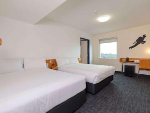 a hotel room with two beds and a window at ibis budget Sydney Airport in Sydney