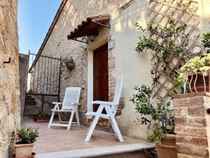 two white chairs sitting outside of a building at Casina di Rosa in Civitella Marittima