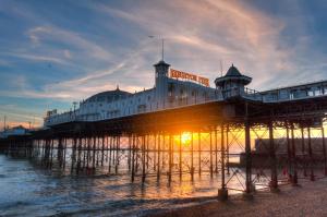 a pier with the sun setting on the water at Camelford Street Cottage - Brighton in Brighton & Hove