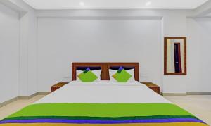 a bedroom with a large white bed with green sheets at Treebo Trend Worldtree Manyata Thanisandra in Bangalore