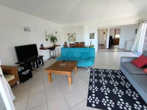 a living room with a blue couch and a table at Surf house holidays in Ruisseau Créole